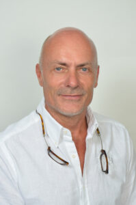 Dr. med. Markus Bruckhaus-Walter, ein weißer Mann ohne Haare, trägt ein weißes Hemd und lächelt leicht in die Kamera.