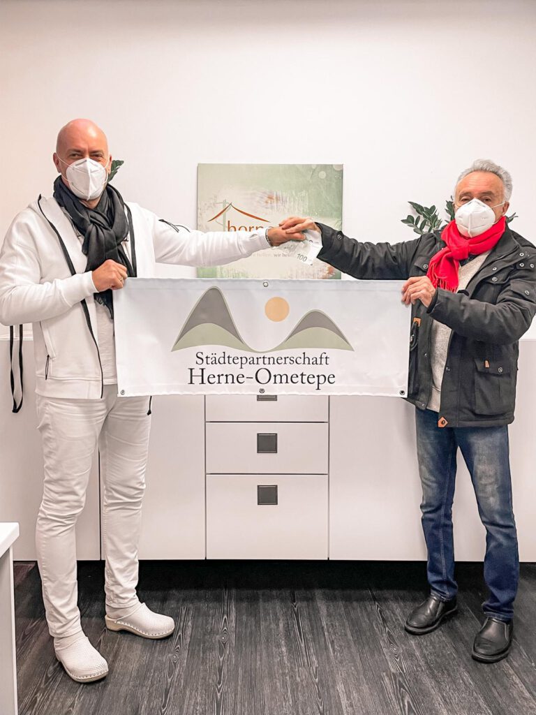 Dr. Bruckhaus-Walter und Udo Jakat (einer der drei Vorsitzenden) halten ein Plakat "Städtepartnerschaft Herne-Ometepe" hoch.